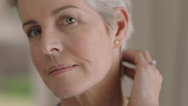 portrait beautiful mature woman looking in mirror at perfect healthy skin touching face with hands enjoying smooth natural complexion with anti aging skincare getting ready at home beauty concept