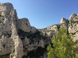 Fototapeta na wymiar View of typical Calanques cliff with sparse vegetation seen from the footpath leading from Luminy to the Calanque de Sugiton in Marseille, France. The Aiguille de Sugiton peak can be seen on the left.