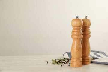 Wooden salt and pepper shakers with napkin on table against white background, space for text. Spice...