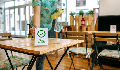 Unrecognizable waitress placing Clean and Safe sign on coffee shop table