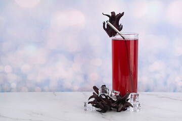 A glass of Roselle drinks with metal straw and whole Roselle fruits