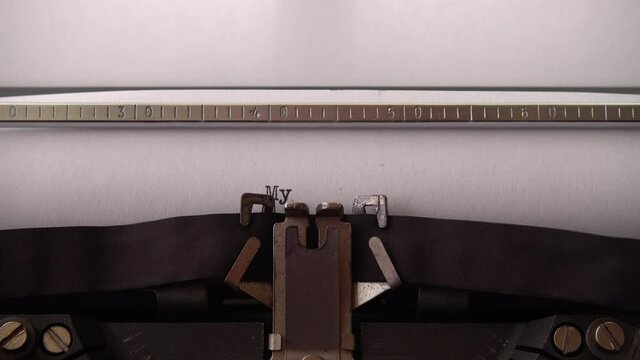 Typing phrase My Story on retro typewriter. Close up.