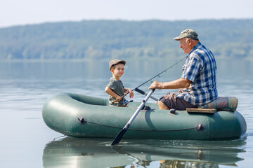 grandfather with grandson together fishing from inflatable boat