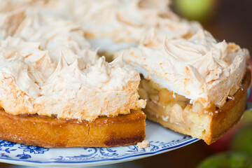 Apple pie with meringue on the top surrounded with green and red autumn apples