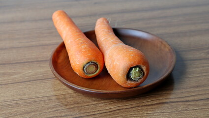 fresh orange carrot on the brown wooden plate 