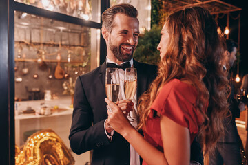 Beautiful young couple in formalwear toasting with champagne while spending time on luxury party