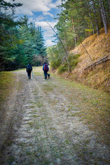 Two people with backpack and dog walking in the apennines. Podere Montebello, Modigliana, Forl&igrave;, Emilia Romagna, Italy, Europe.
