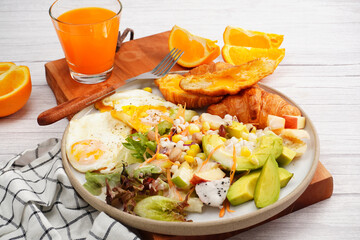 Croissant, fried egg, fresh green salad with fresh orange juice, breakfast