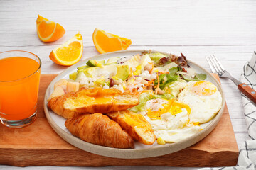 Croissant, fried egg, fresh green salad with fresh orange juice, breakfast