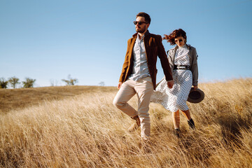 Young couple in love walking outdoors on a sunny day. The man gently hugs the woman. Love story. Autumn style.