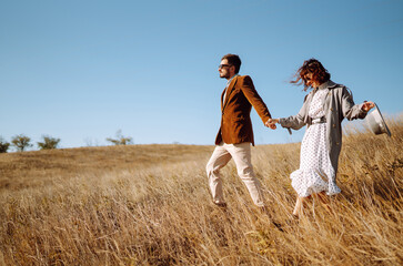 Young couple in love walking outdoors on a sunny day. The man gently hugs the woman. Love story. Autumn style.