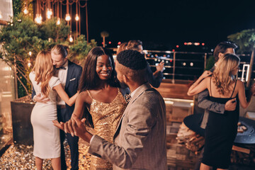 Beautiful young people dancing and smiling while spending time on luxury party