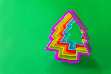 Multi-colored forms for cookies in the form of a Christmas tree on a green background. Christmas baking set.