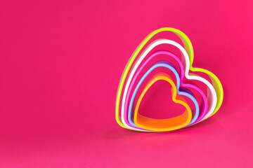 Multicolored heart shaped cookie cutters on a pink background