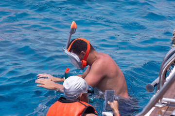 tourists in masks swim in the sea. red sea, egypt, sharm el sheikh. the man has a phone for...