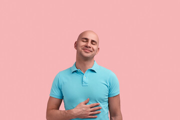 Happy dreaming bald homosexual man with bristle is in romantic mood, smiles, closes eyes in...