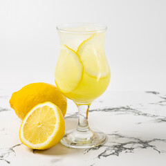 Limoncello cocktail with lemon in a beautiful glass on a light background and a marble table