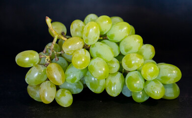 Ripe green sultana raisin with water drops. Fresh grapes on the dark background. Minimalistic...