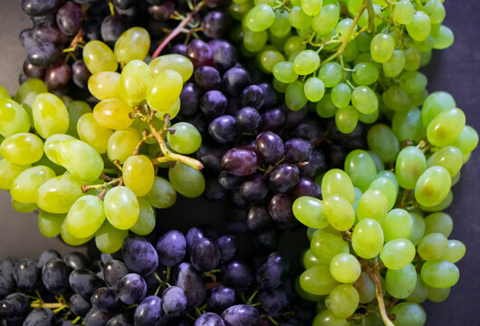 Ripe green and blue grapes mix. Fresh grapes on the dark background. Minimalistic grapes close-up shot. 