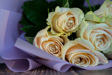 Tender ivory roses bouquet. Fresh white roses composition with water drops. Selective focus of the floristic composition. Gift concept. Bouquet of beautiful roses on a dressing table.