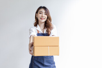 Asian woman standing holding parcel boxes, she owns an online store, she packs and ships through a private transport company. Online selling and online shopping concepts.