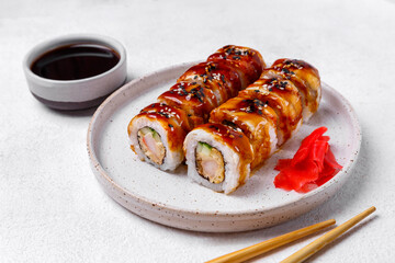 sushi rolls with shrimp, smoked eel, ginger and soy sauce on a white plate