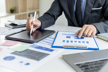 Businessman is using tablet to compare information on financial documents, he is checking company financial documents in office, company financial statements. Concept of financial management.