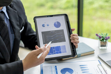 Businessman holding a tablet showing sales data of a salesperson, he is meeting with the sales manager to plan sales growth management, marketing plan to increase sales. Sales management concept.