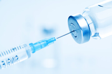 Medical syringe with a needle and a bollte with vaccine.