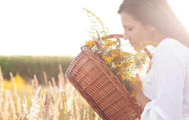 Attractive woman sniffs bouquet of flower herb on open air. Copy space for text.