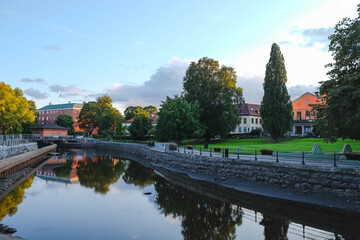The view of river banks, lawn and old buildings in the center of small old Swedish town Vasteras shot in the evening on clear September day