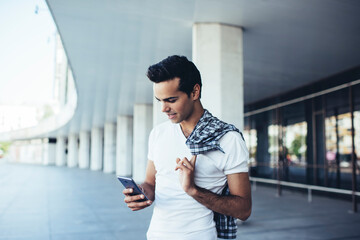 Handsome hipster guy in casual outfit connecting to internet for chatting and messaging in social...