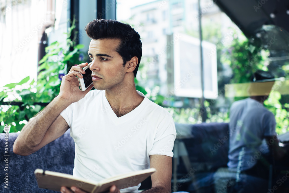 Poster contemplative caucasian student with education textbook using roaming internet connection for roamin