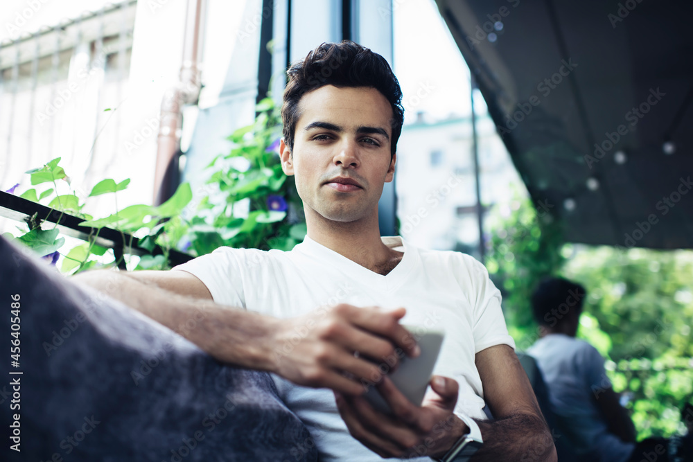 Poster portrait of male with smartphone device looking at camera while creating network content, blogger ho