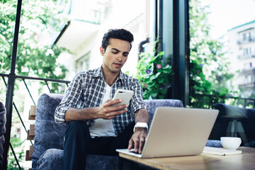 Caucasian freelance copywriter using smartphone and laptop for sharing media files via bluetooth...