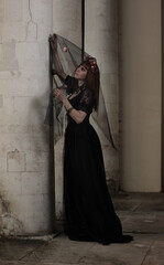Gothic woman in mysterious place, long black victorian dress create dramatic atmosphere. Classic horror scene