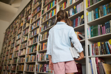 Young Caucasian girl with textbooks at the library