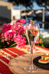 Drinking of white cold champagne, bliny with red caviar and view on Port Grimaud near Saint-Tropez in summer