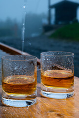 Glasses of strong scotch single malt whisky and rain water drops