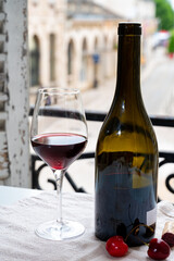 Tasting of burgundy red wine from grand cru pinot noir  vineyards, glass and bottle of wine and view on old town street in Burgundy wine region, France