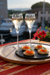 Russian style party with two glasses of white cold champagne, bliny with red caviar and view on Port Grimaud near Saint-Tropez in summer