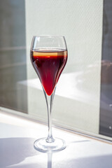 Drinking of Kir Royal,  French aperitif cocktail made  from creme de cassis topped with champagne, typically served in flute glass, with view on old French village