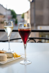 Drinking of Kir Royal,  French aperitif cocktail made  from creme de cassis topped with champagne, typically served in flute glass, with view on old French village