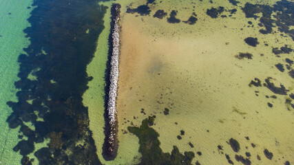 Luftaufnahme von einem von Wasser umgebenen Steinwall im Meer mit Vögeln