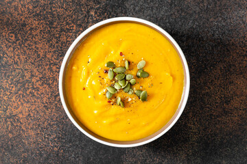 Pumpkin cream soup with seeds top view on a dark background. Traditional autumn vegetarian dish on...