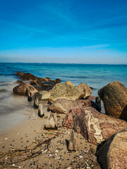 Fototapeta na wymiar Steinreihe am Strand ins blaue Meer übergehend