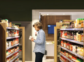 Young man shopping in supermarket, reading product information