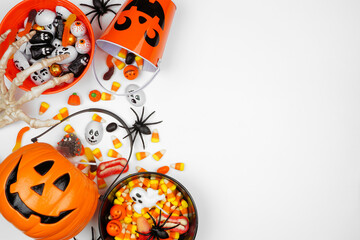Halloween trick or treat side border with jack o lantern pails and assorted candy. Overhead view on...