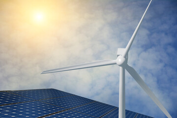 Wind generator turbine and solar panels against blue sky background with white clouds. Blurred...