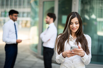Businesswoman using her smartphone in front of her office